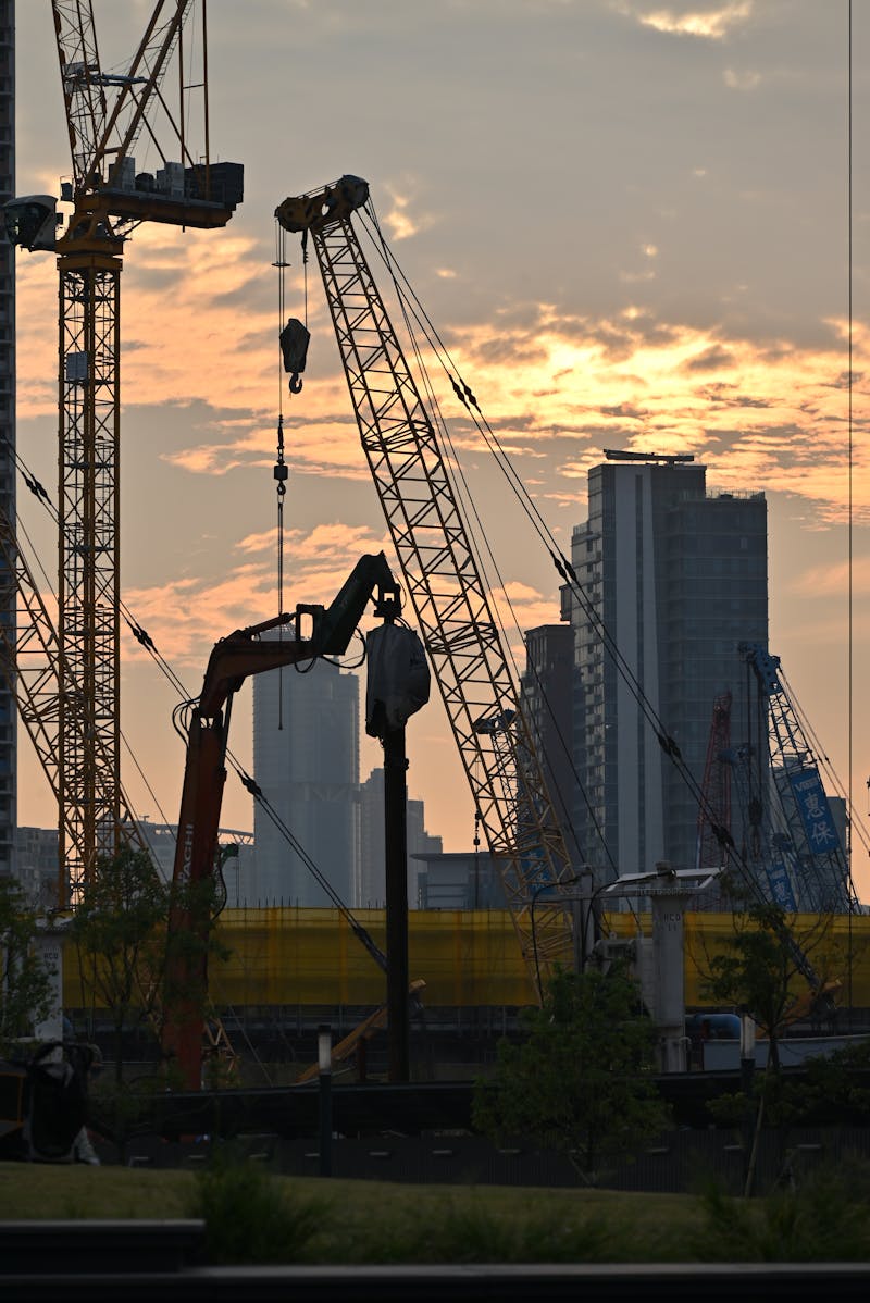 Construction cranes at dusk on urban site