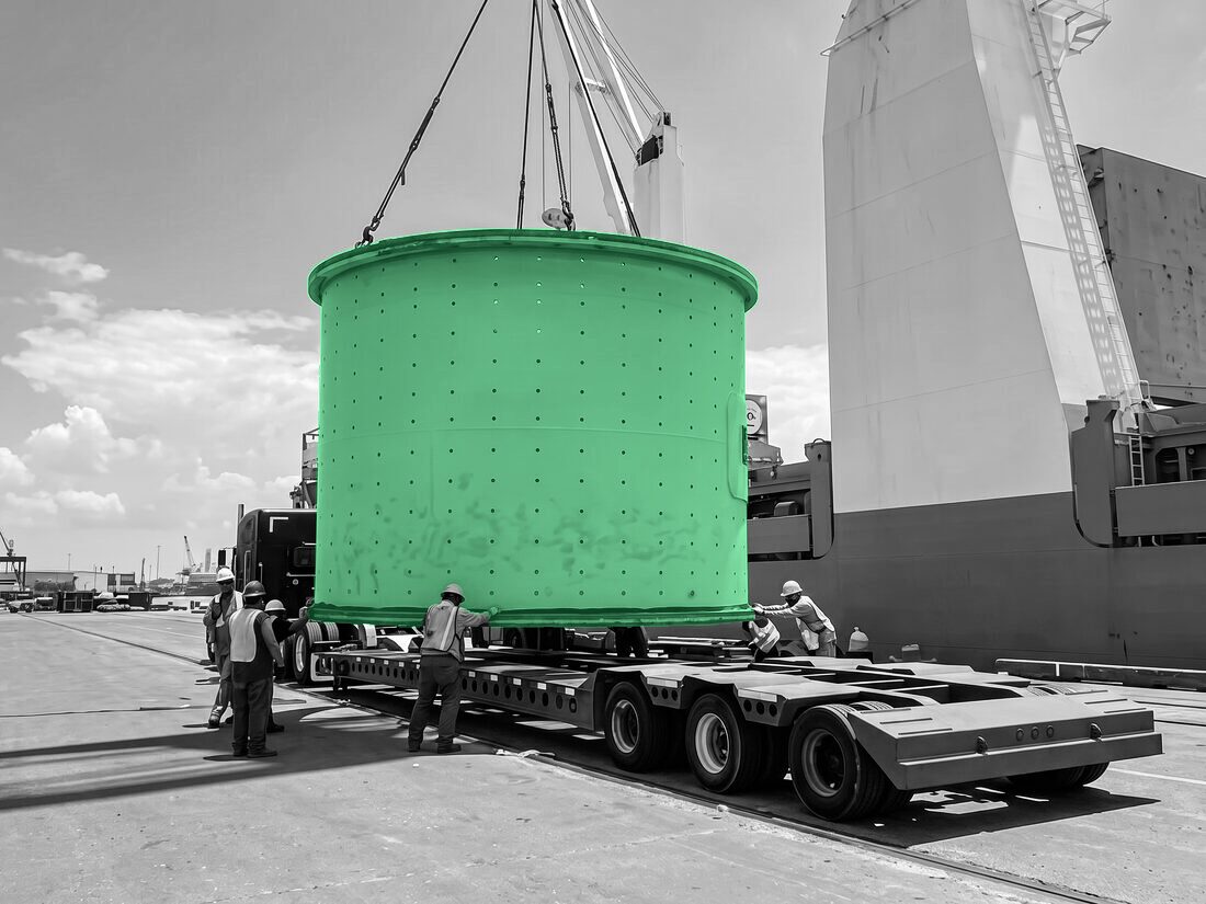 Green mill shell being lowered onto a modular trailer at port