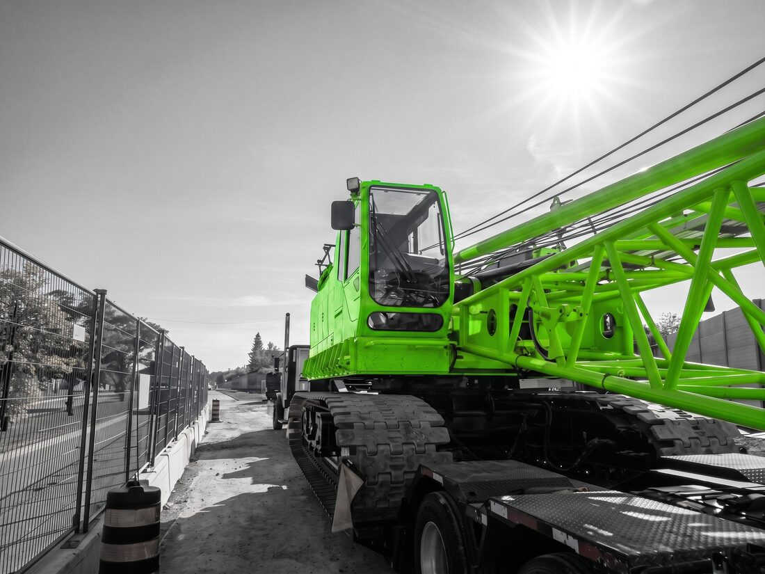 Kobelco crawler crane loaded on low-bed trailer at street-side job site