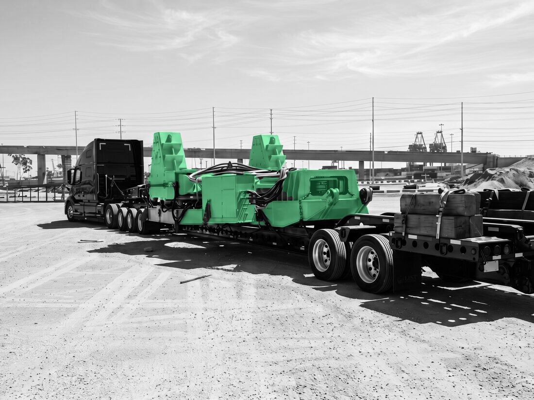 Orange horizontal directional drilling (HDD) rig / pipe-handling equipment on low-bed trailer at port