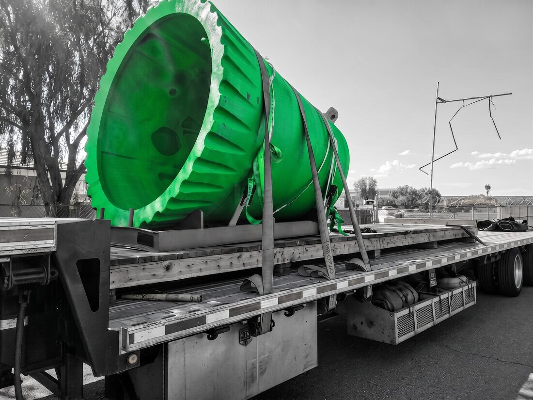 Large teal heat exchanger / vessel head on red transport skid on flatbed