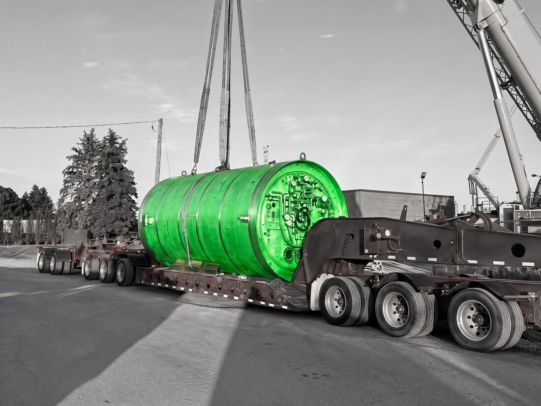 Tunnel boring machine cutterhead suspended in slings above red multi-axle trailer