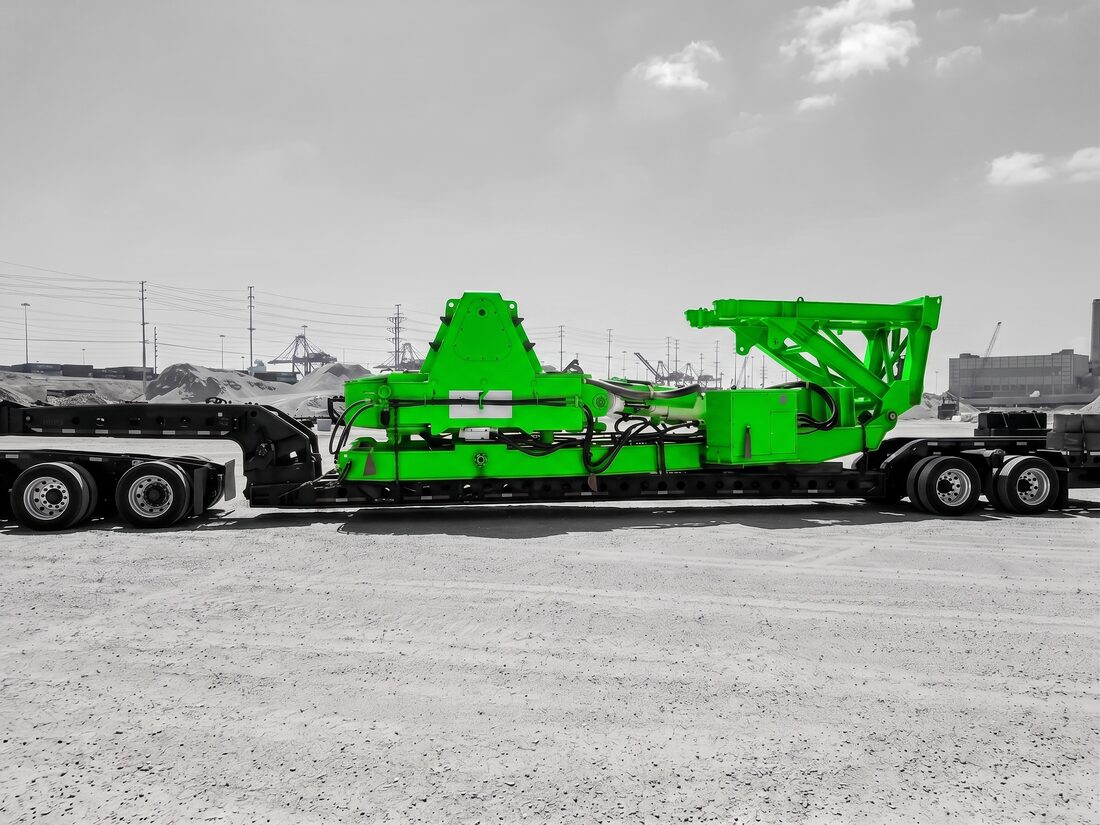 Orange Sandvik ROC blast-hole drill (mast folded) on lowboy at industrial yard