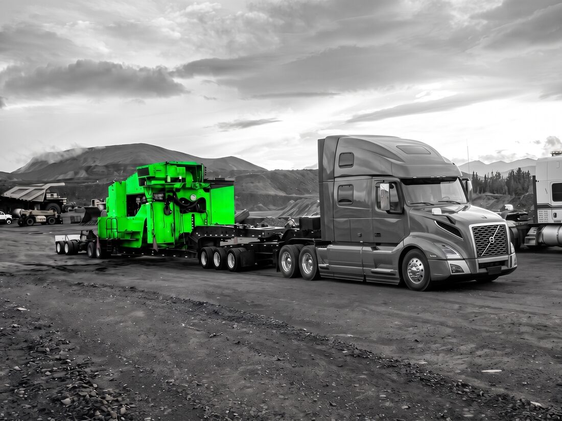 Yellow ROC drill rig house on lowboy with Western Star tractor at mine staging area