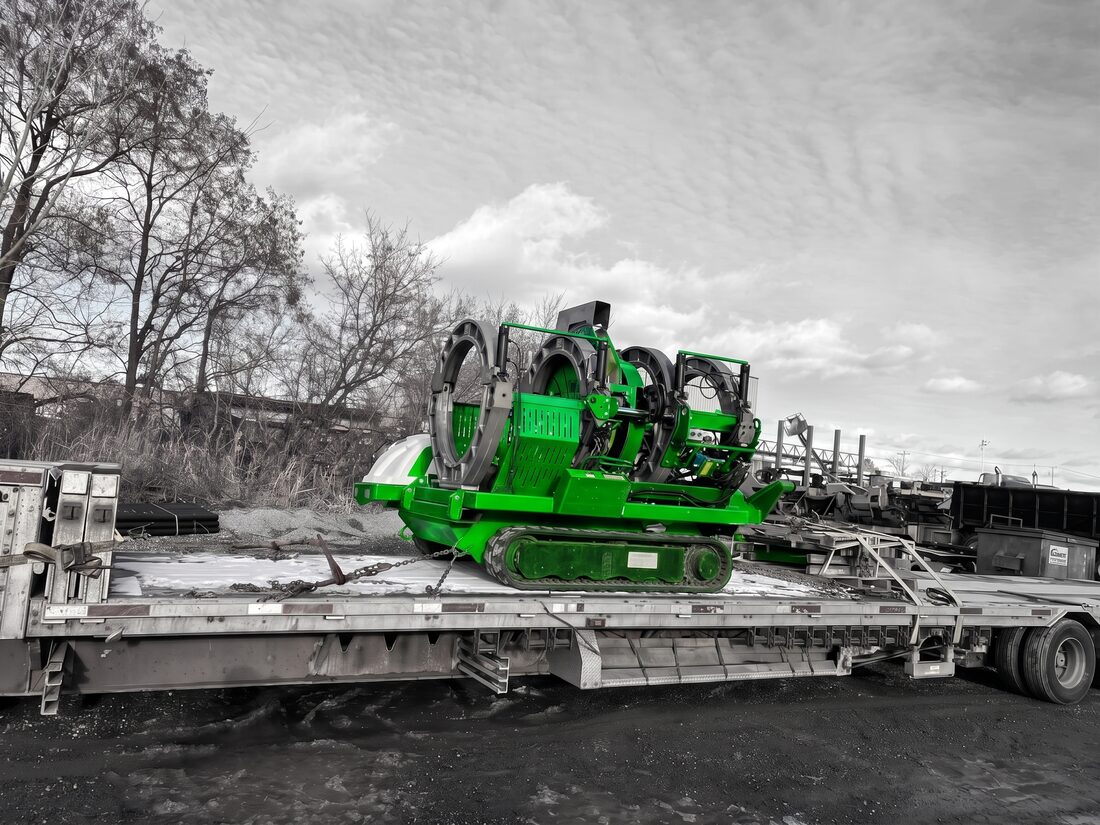 Green Vermeer tracked horizontal directional drill secured on stepdeck at winter site