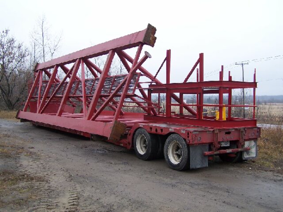 Red structural steel truss / conveyor or building frame on double-drop trailer