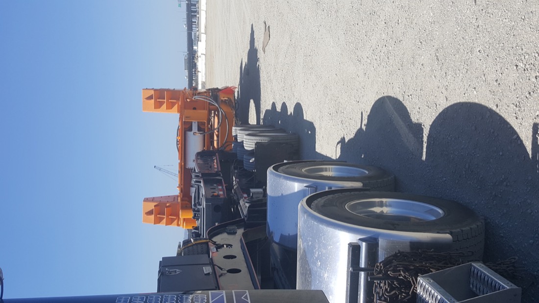 Same orange HDD / pipe-handling rig from different angle on multi-axle low-bed trailer