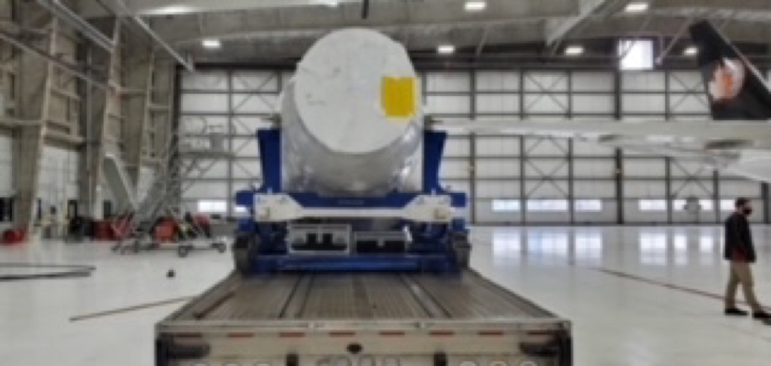 White cylindrical pressure vessel / tank — head-on view on blue cradle in warehouse