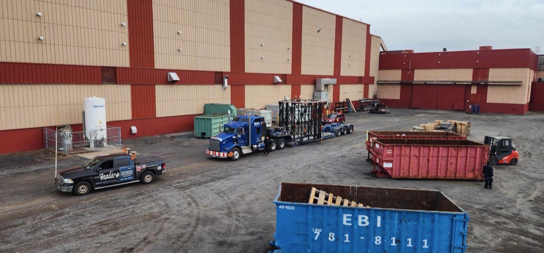 Aerial view — blue Kenworth with structural steel cage / rebar framework on low-bed in industrial yard