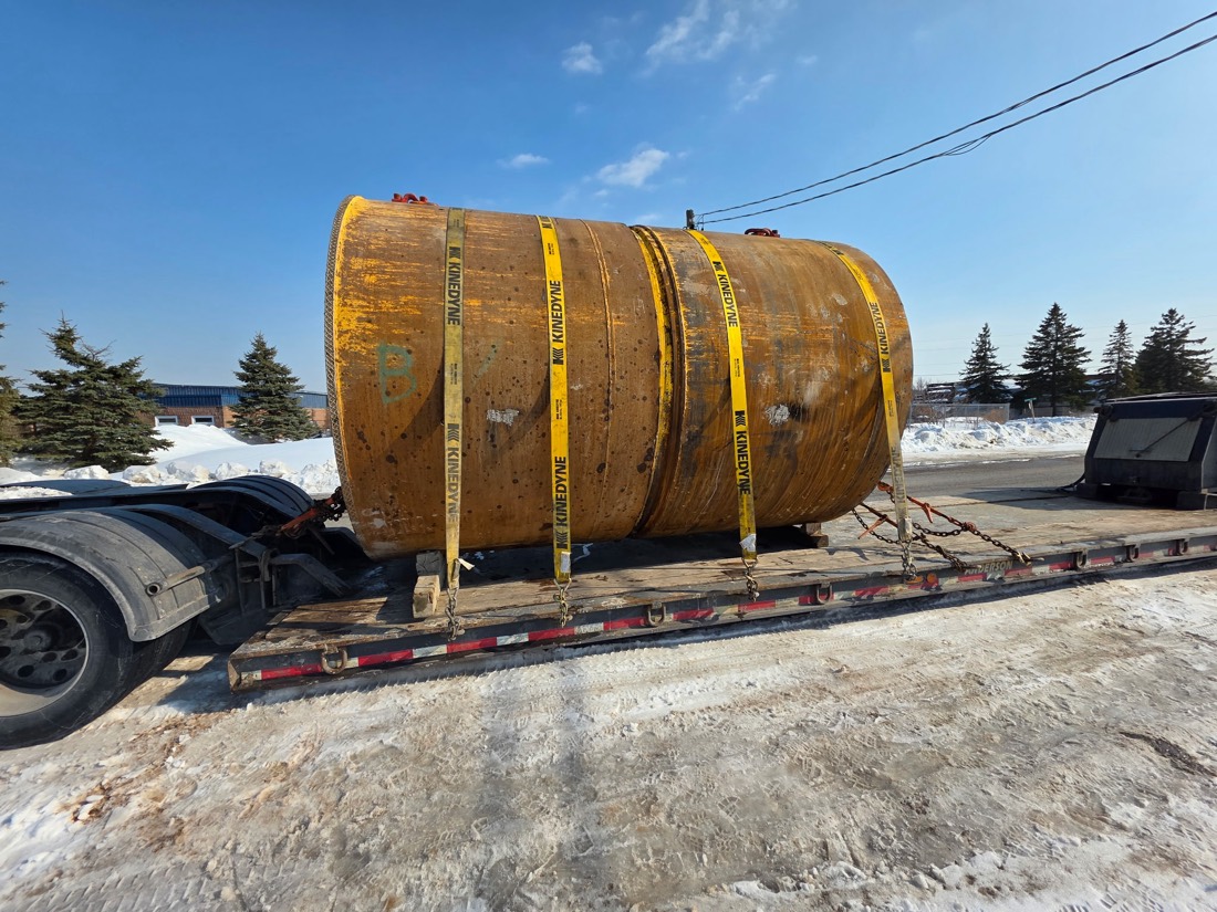 Yellow steel drum / mill or kiln section strap-secured on step-deck flatbed (winter)