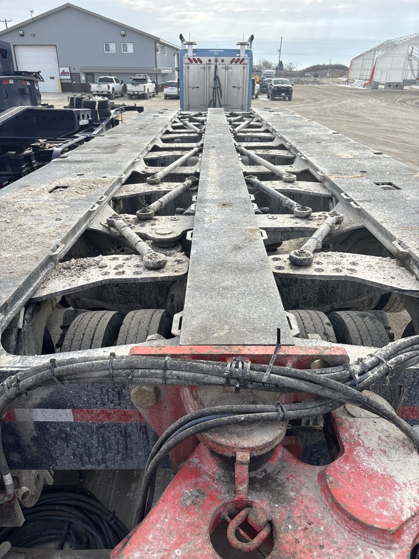 View down empty deck-frame of heavy-haul modular trailer from tractor's rear