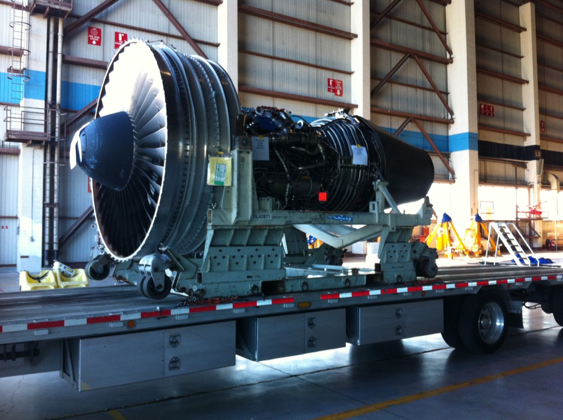 Large turbofan jet engine on transport stand on flatbed inside aircraft hangar