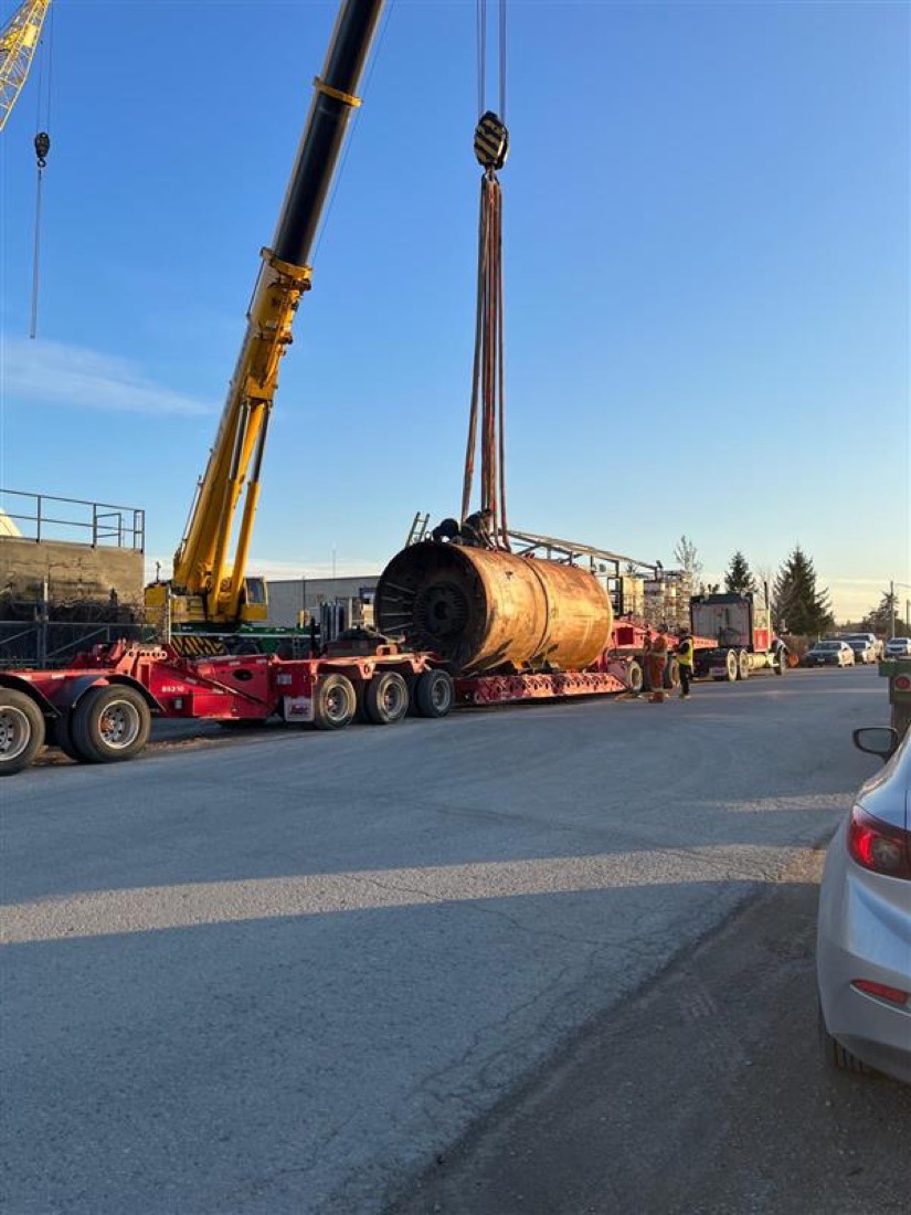 Same rusty TBM drum being lowered onto Aspen modular trailer by yellow mobile crane