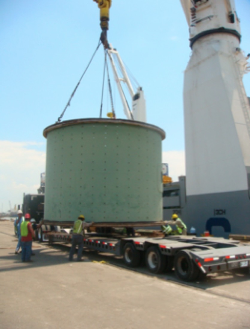 Green mill / crusher shell section being lowered onto modular trailer at port (duplicate of 11.png)