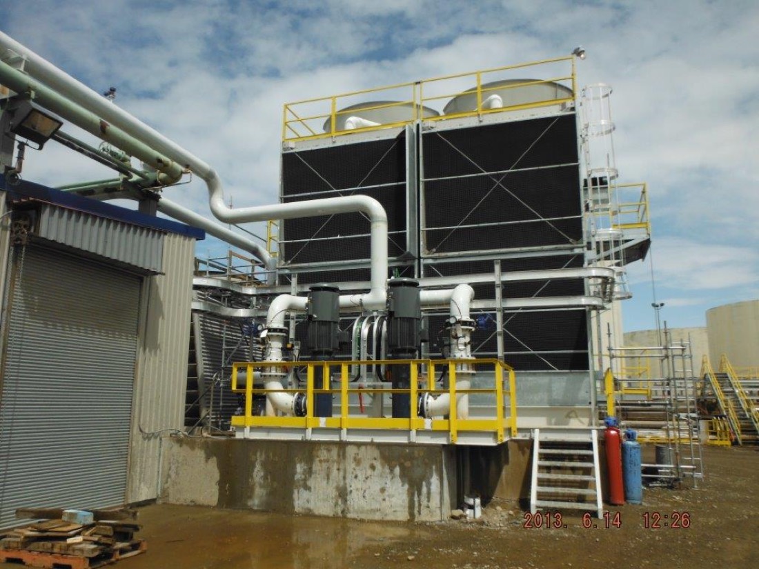 Completed two-cell cooling tower with pumps and piping at refinery