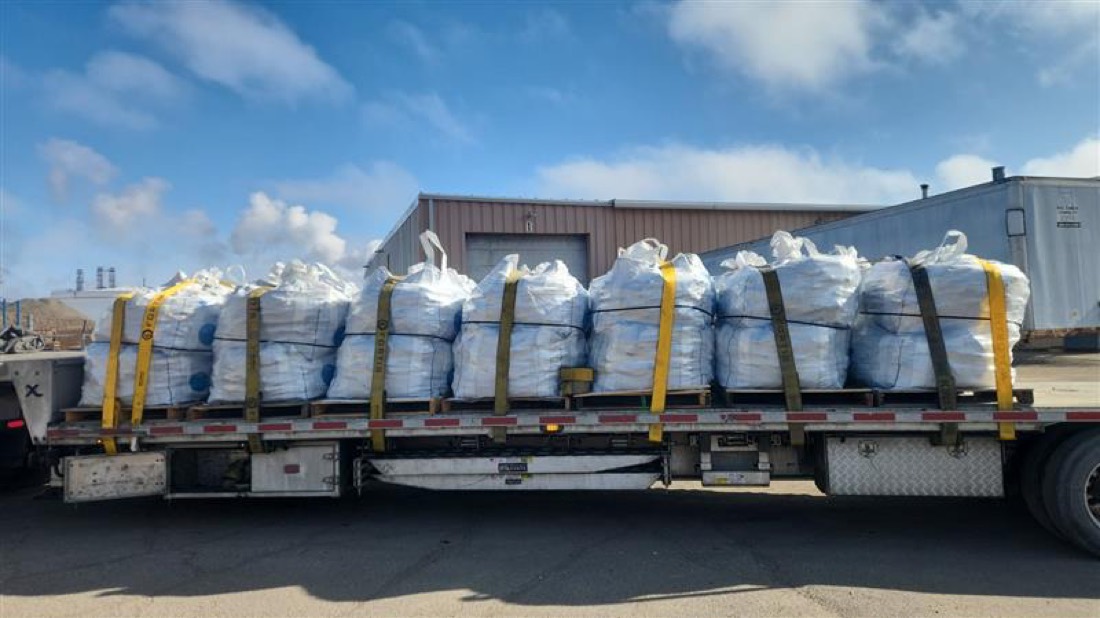 Flatbed loaded with rows of white super sacks (FIBC bulk bags) on pallets