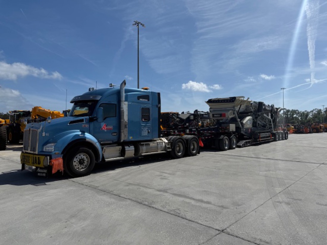 Blue Kenworth with mobile crusher / screening plant on Anderson lowboy at equipment yard