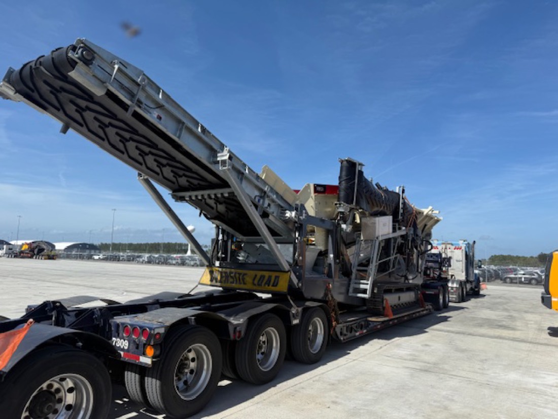 Tracked mobile screening plant with raised conveyor on OVERSIZE LOAD lowboy trailer