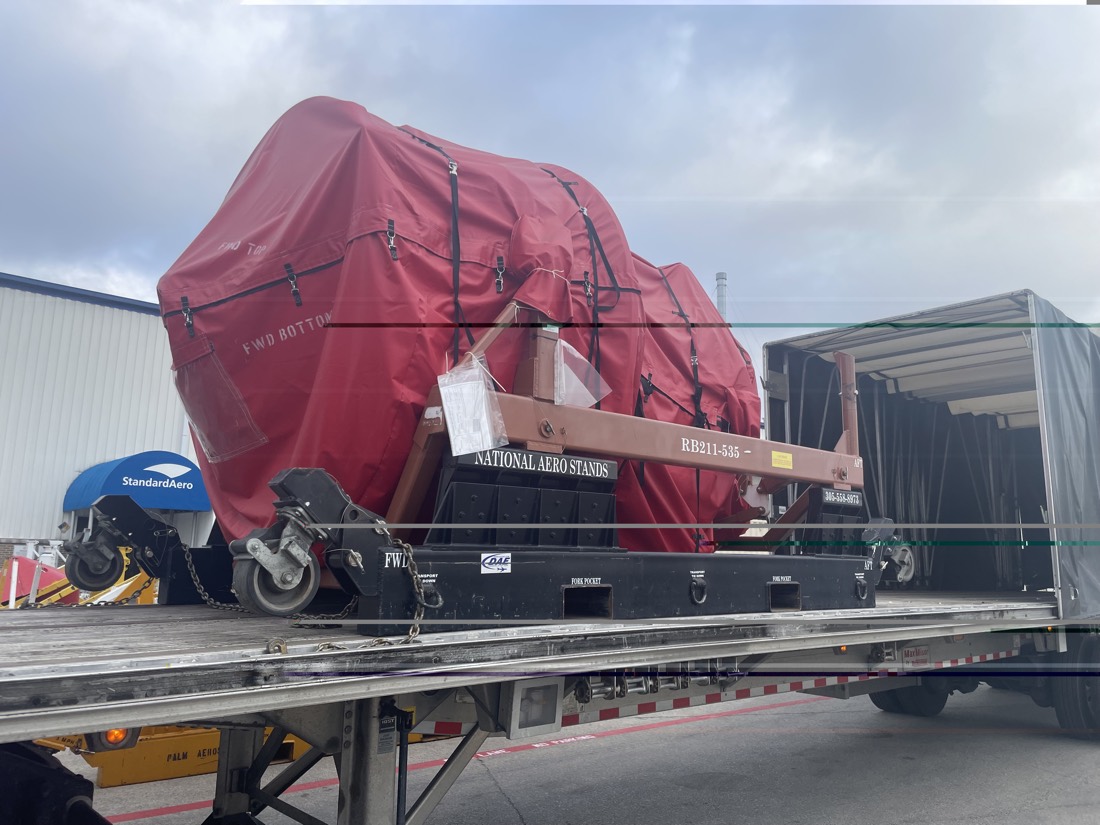 Red-tarped Rolls-Royce RB211-535 jet engine on National Aero Stands transport stand at StandardAero MRO