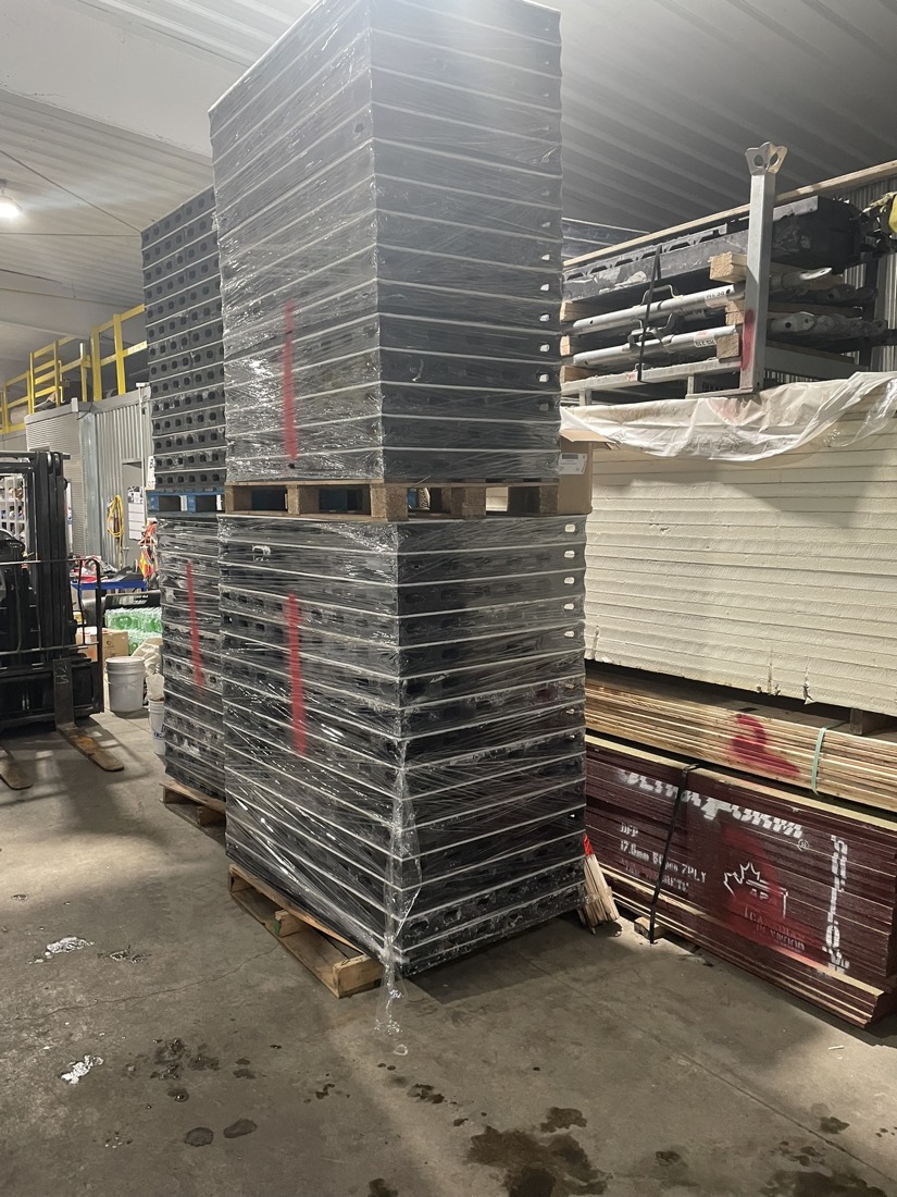 Tall stacks of steel grating / decking panels on pallets in warehouse