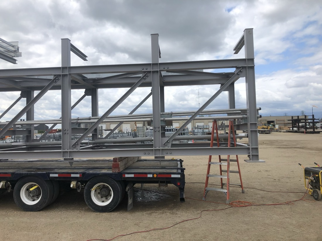 Closer view of structural steel building/process plant skeleton on flatbed at fab yard