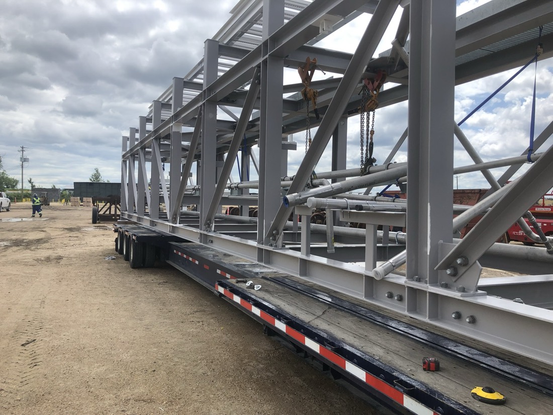 Same structural skeleton on flatbed with chain hoists hooked up at fab yard