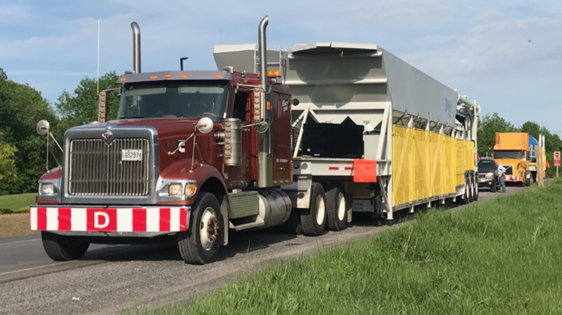 Burgundy International tractor with long industrial conveyor / screening plant on flatbed (Quebec)