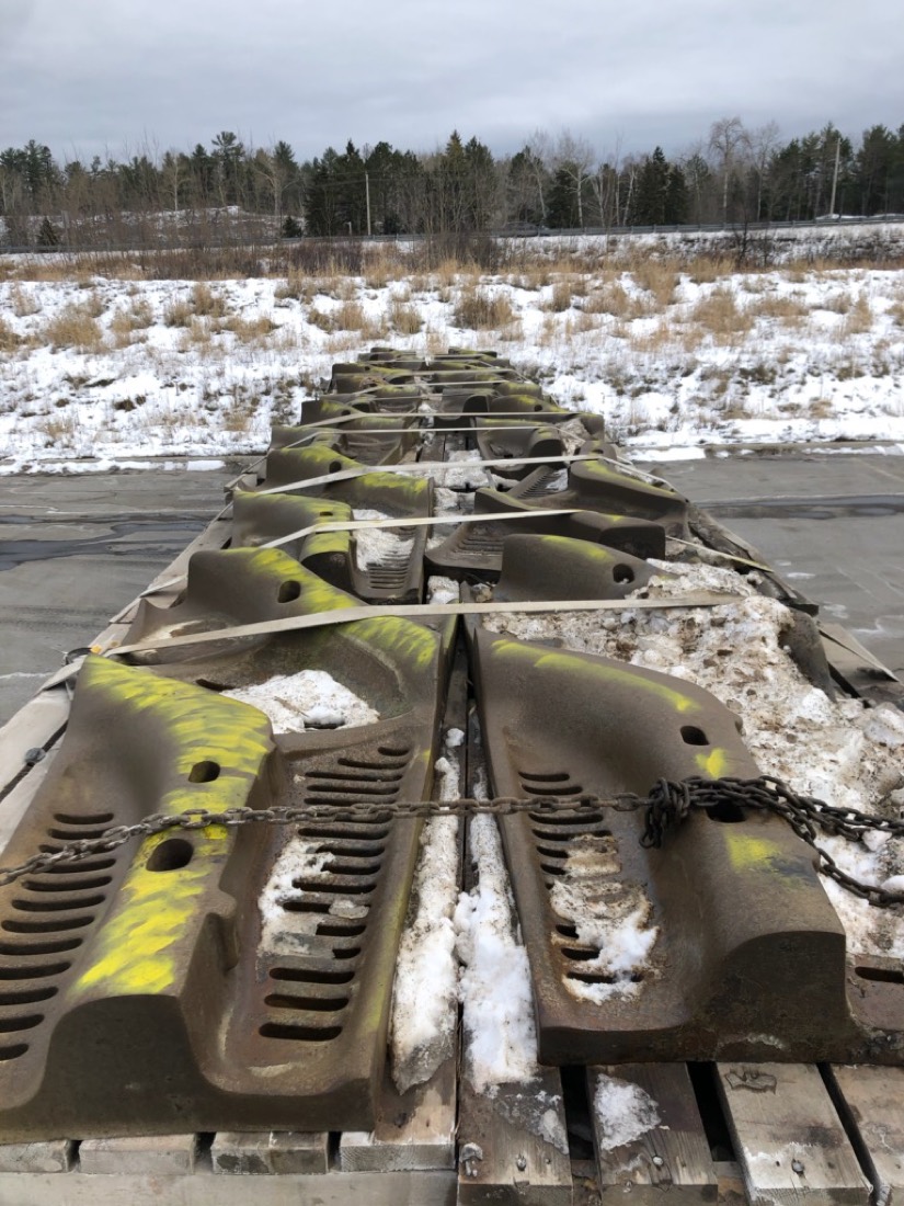 Row of mining mill liners (lifter bars / discharge grates) on flatbed in winter