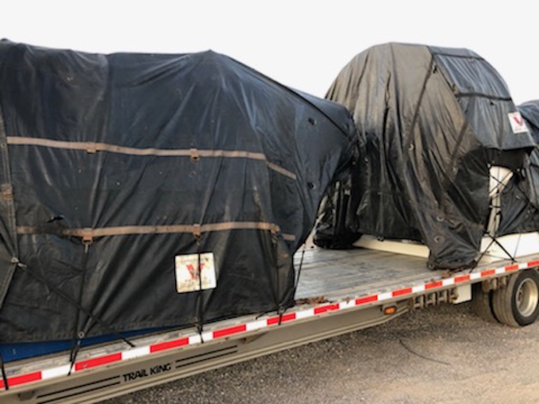 Two tarp-wrapped industrial loads on Trail King step-deck flatbed