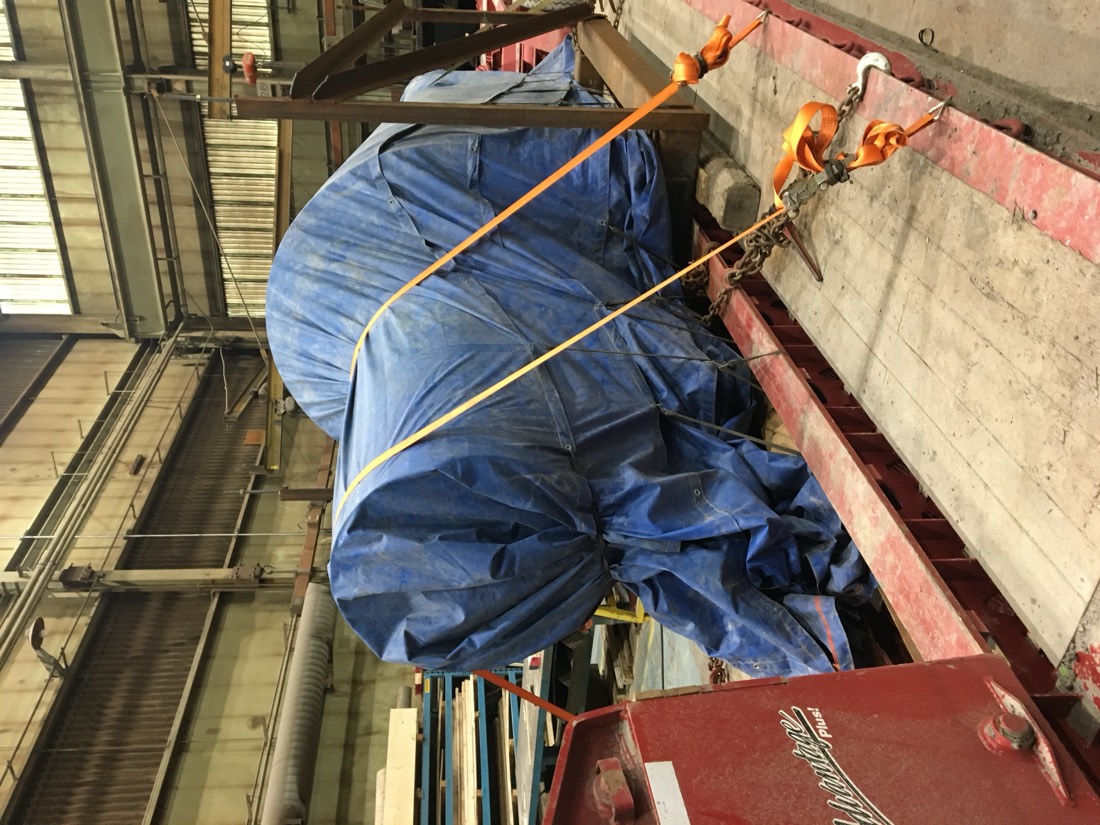 Blue-tarp-wrapped industrial cargo strap-secured on flatbed in shop