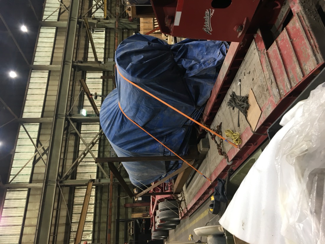 Same blue-tarp cargo on red trailer — end view in fab shop