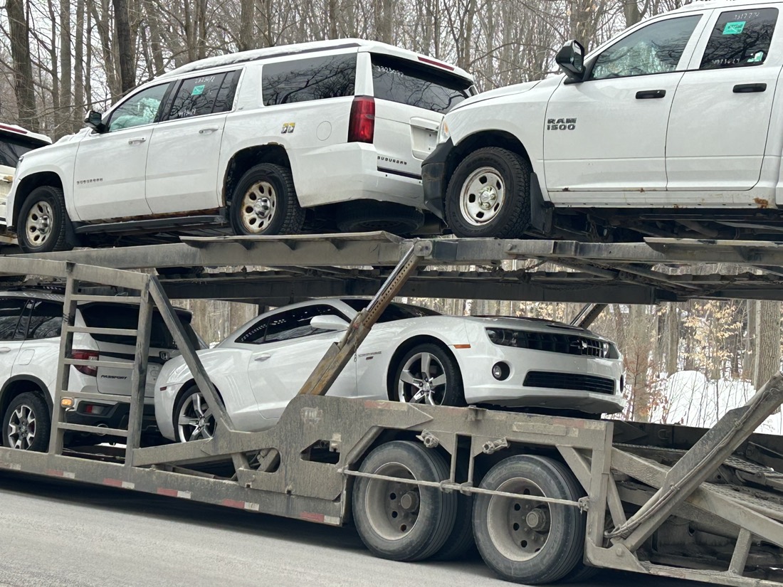 Multi-level auto transport with white Suburban, Ram 1500, Camaro