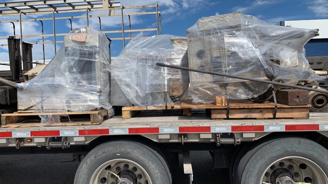 Multiple shrink-wrapped drilling equipment pallets on flatbed