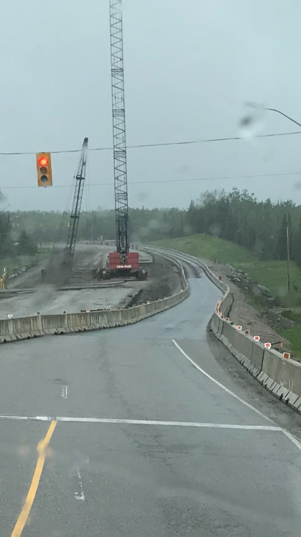 Link-Belt lattice crawler crane with tall boom at rainy highway construction site