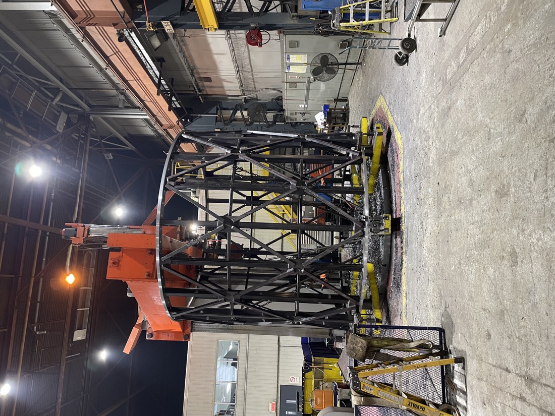 Cylindrical structural steel cage being assembled in fabrication shop
