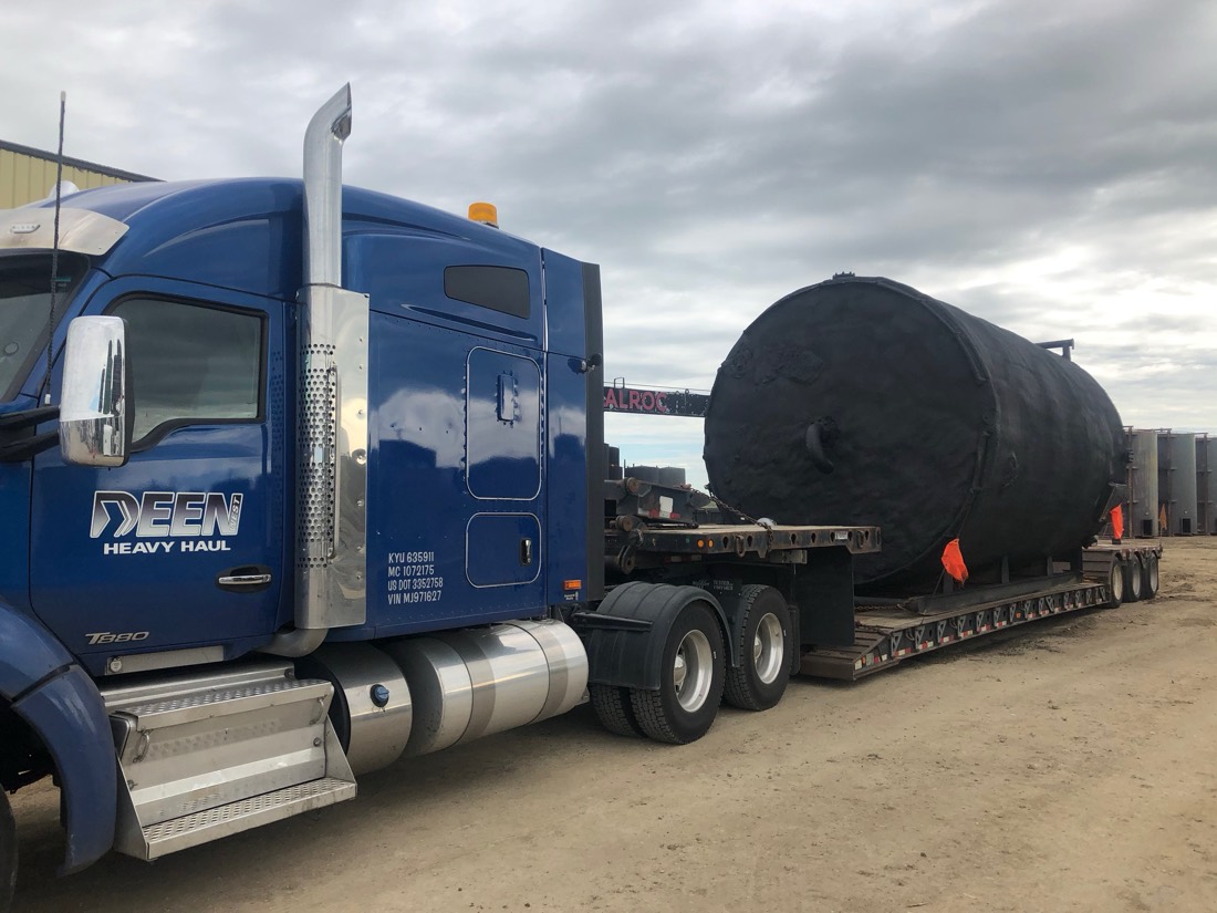 Same black-coated tank on Deen Heavy Haul lowboy with blue Kenworth T880 tractor