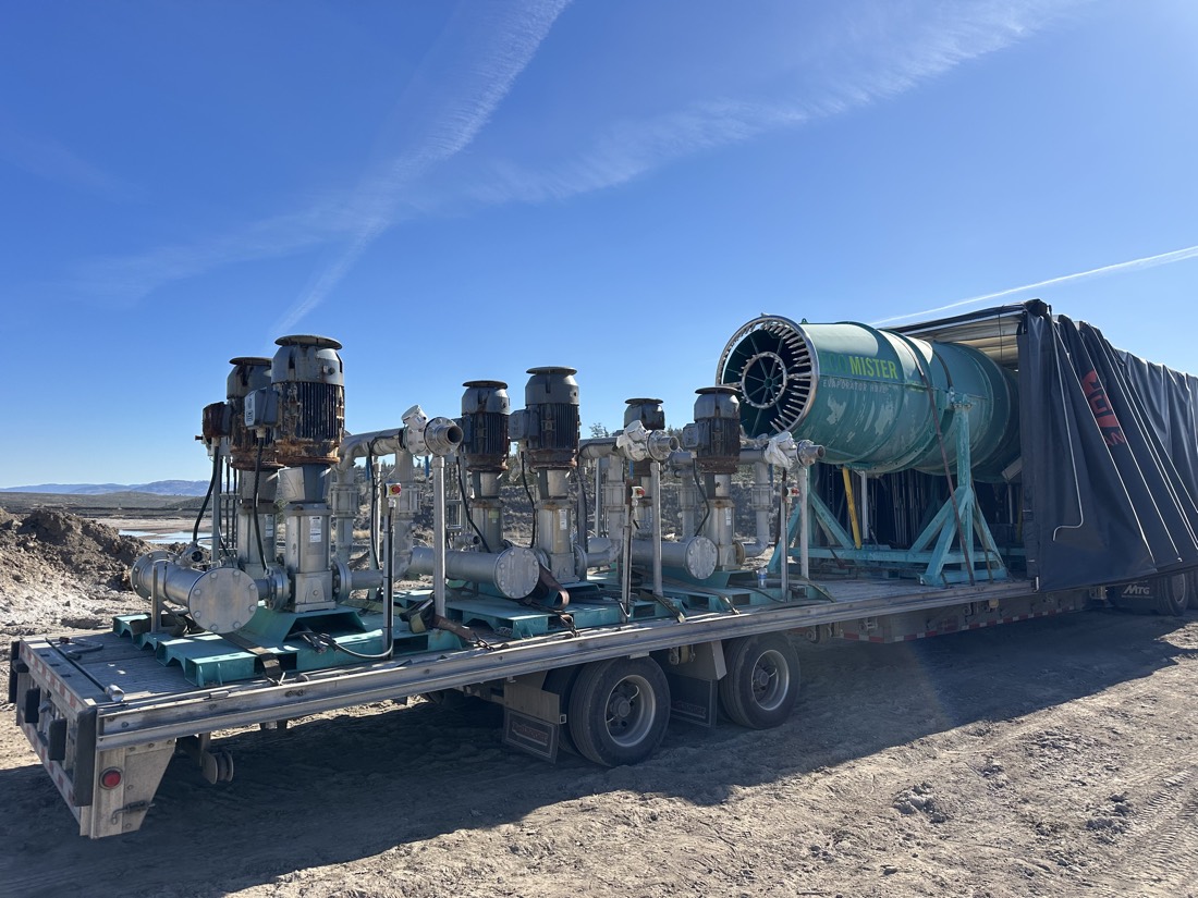 Multiple EcoMister dust-suppression cannons + vertical pump skids on Conestoga flatbed at mining site
