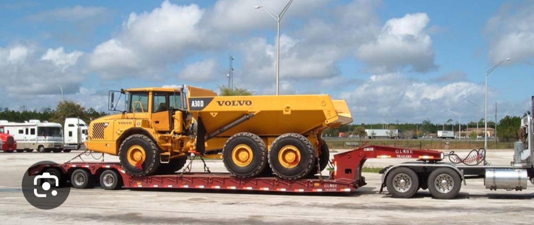 Yellow Volvo A30D articulated mining dump truck on Globe Trailers lowboy at rest stop