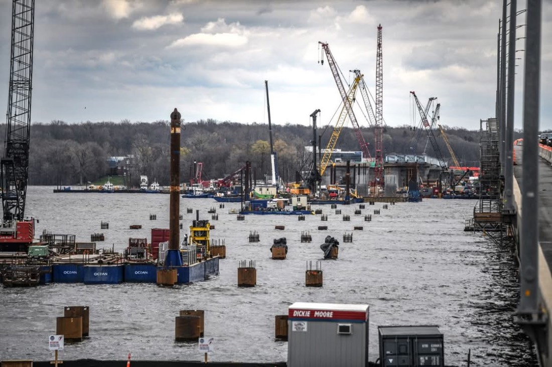 Île-aux-Tourtes bridge construction — multiple crawler cranes and Ocean barges with piers in river
