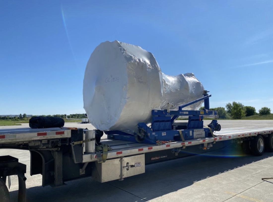 GE jet engine (CF6) in silver shrink-wrap on blue Cargojet stand on step-deck flatbed