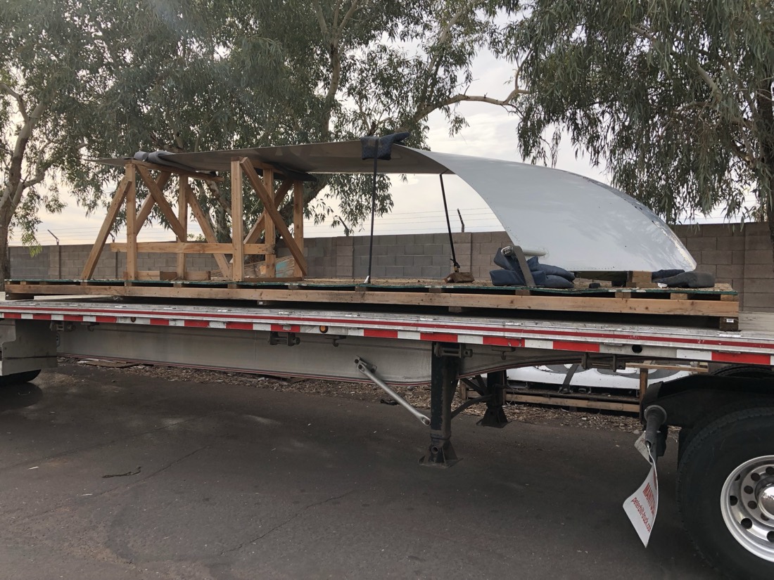 Fiberglass boat hull / canopy on wood cribbing on flatbed