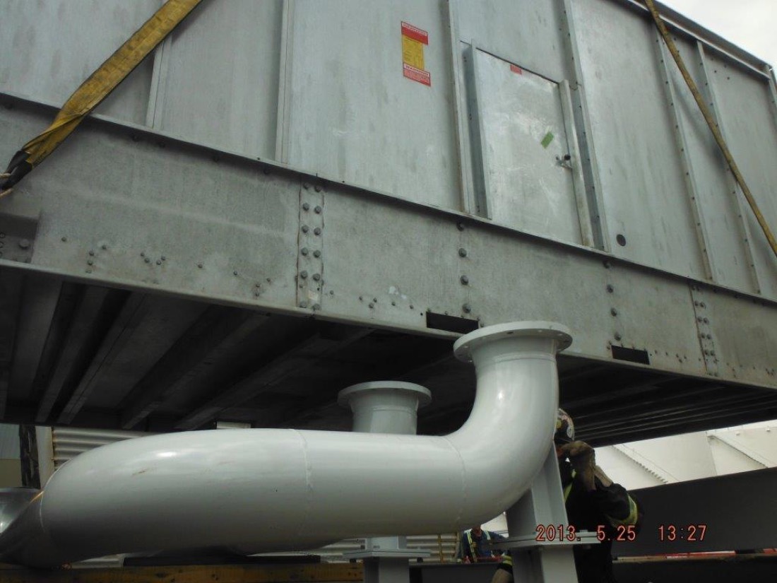 Cooling tower module being placed onto white piping manifold at refinery