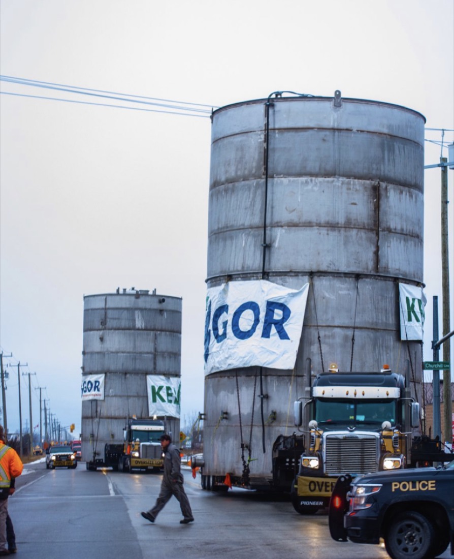 Two oversized cylindrical process vessels in convoy with police escort through town