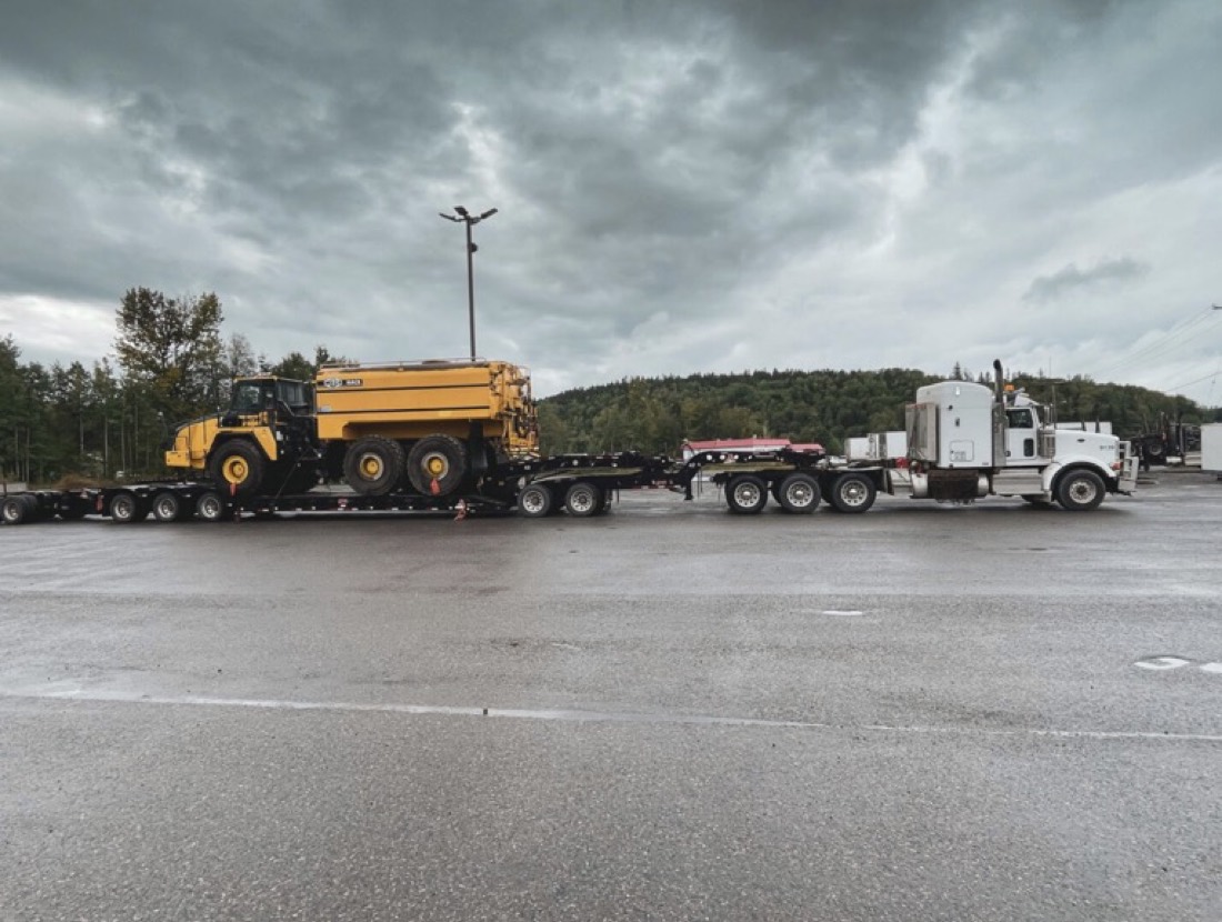 Cat articulated haul truck on multi-axle lowboy, Peterbilt tractor at rest