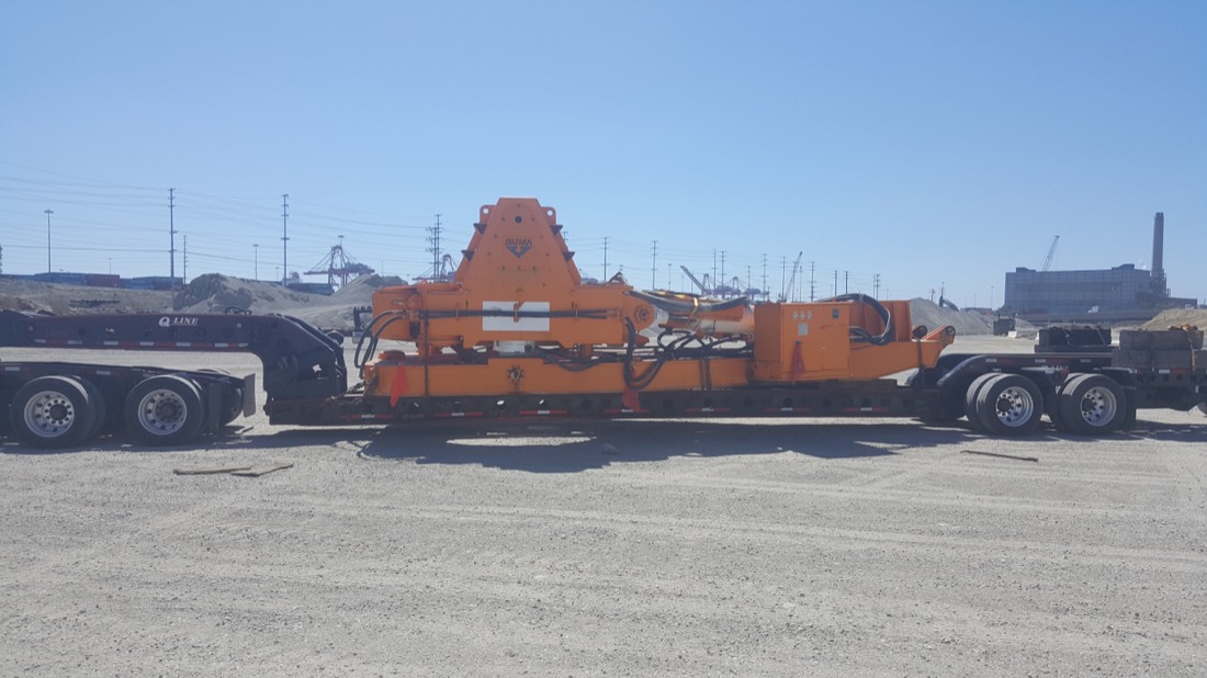 Orange Martin Engineering hammermill or breaker unit on lowboy at industrial yard