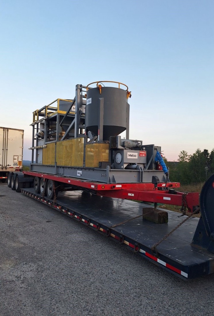 Metso skid-mounted hydraulic power unit and hopper on lowboy at dusk