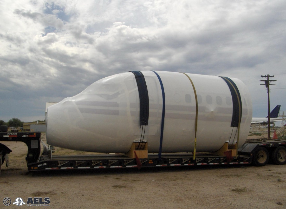 Shrink-wrapped commercial airliner forward fuselage / nose section on lowboy (AELS)