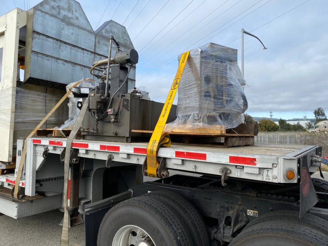 CBS Parts shipment — close-up of wrapped sub-assembly strapped beside ducting on flatdeck