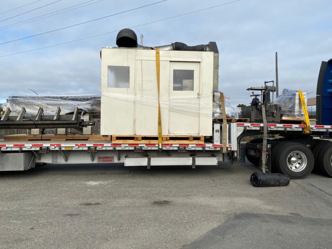 CBS Parts shipment — operator booth with HVAC duct strapped beside conveyor frame on stepdeck