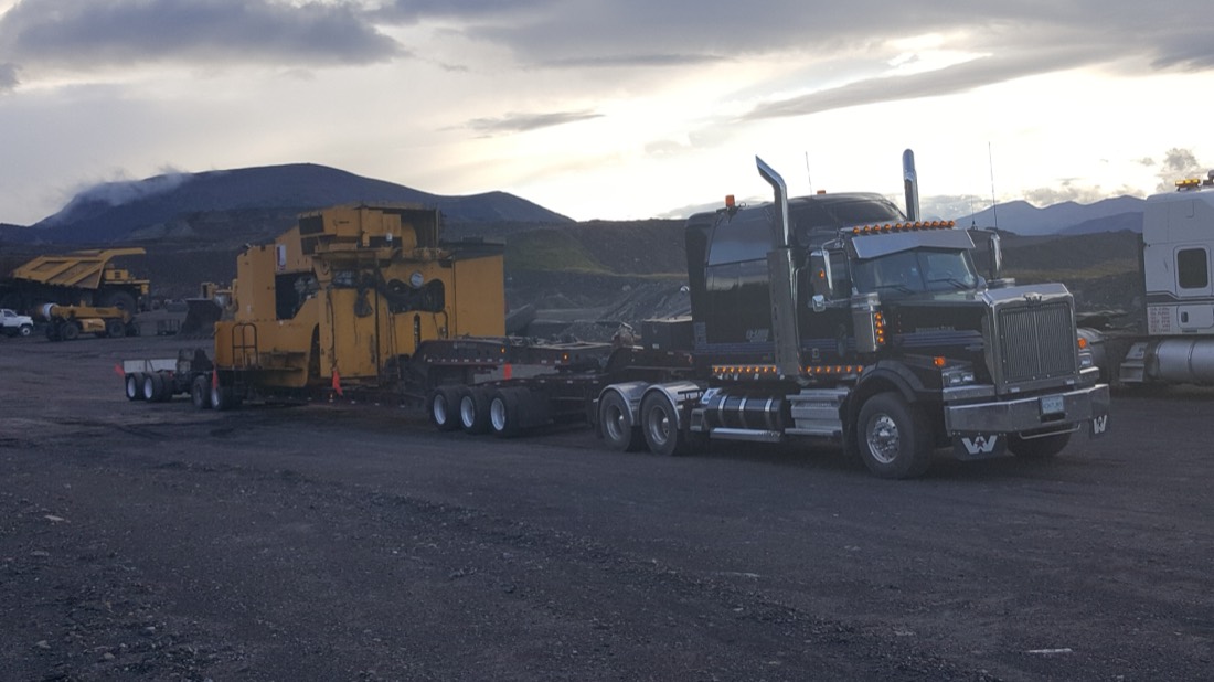 Yellow ROC drill rig house on lowboy with Western Star tractor at mine staging area